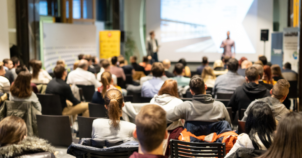 Image of a busy event space with audience and speaker