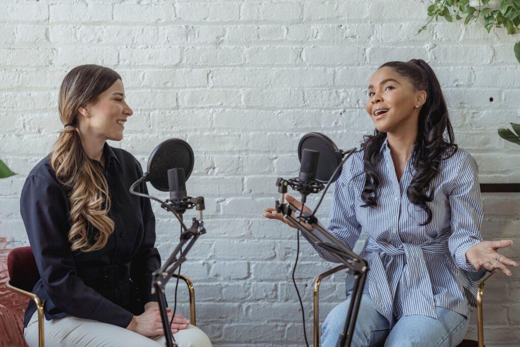 Challenging events industry on equity, diversity and inclusion at events. A white woman and a black woman talking together in front of microphones.