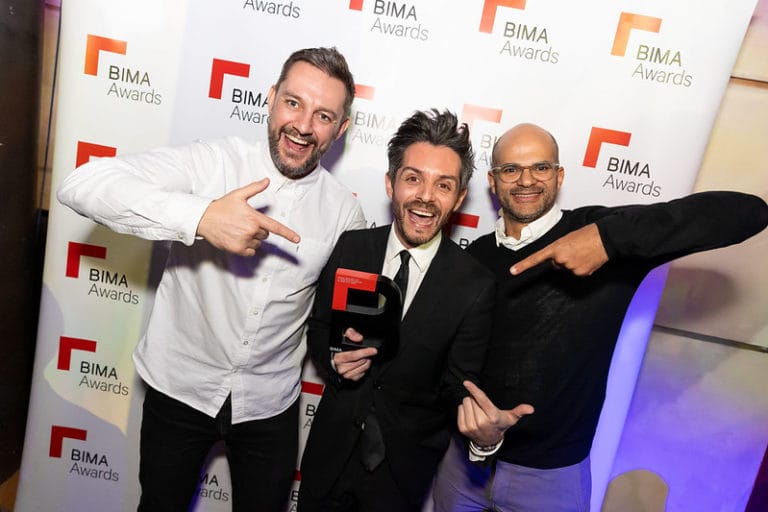 Group of 3 men pointing at their BIMA award