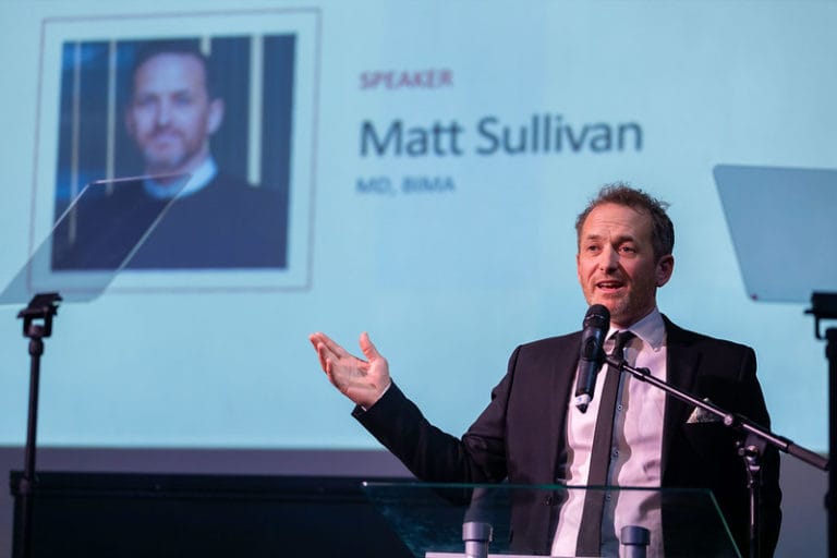 Image of Matt Sullivan, MD of BIMA, on stage, talking with his title slide on the screen behind him