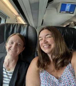 image of two women sitting in train seats facing the camera and smiling